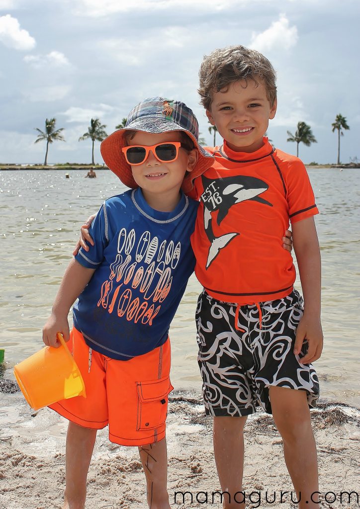 Two boys hug each other on the beach.