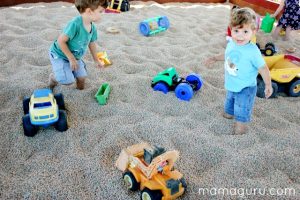 Two boys play with Tonka trucks in a dried bean pit, like a sandbox.